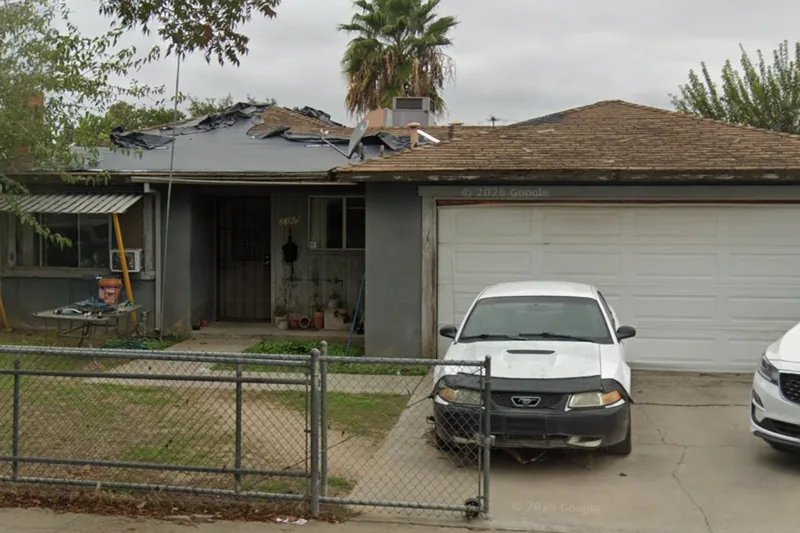 A home on the Fresno County tax-sale list with a failing, tarped roof