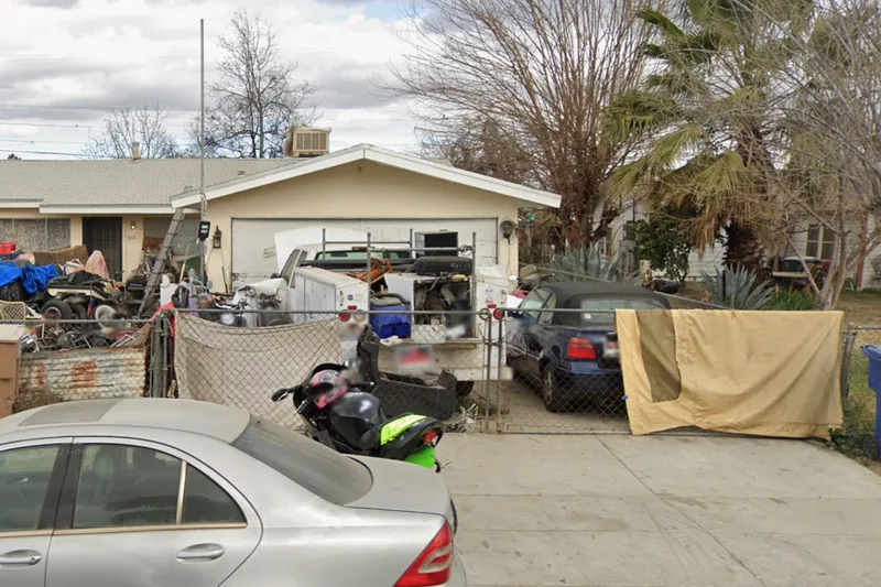 A distressed property on the Kern County tax-sale list, yard stacked with vehicles and stored material